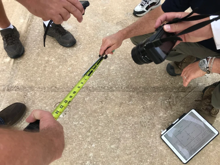 Inspectors measuring and photographing impact marks on a flat roof