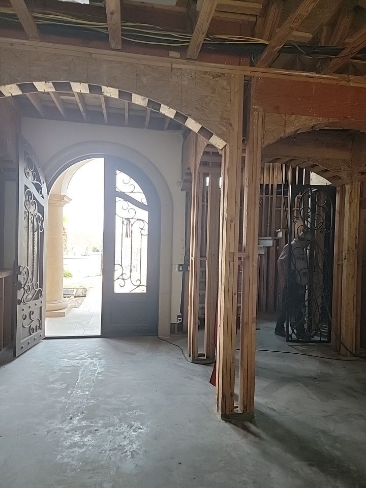 Arched residential entry with exposed wall framing and ceiling structure during reconstruction