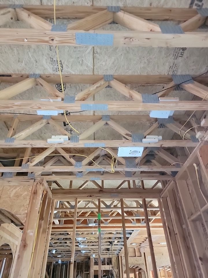 Open residential ceiling showing wood framing, metal connectors, and building systems during inspection